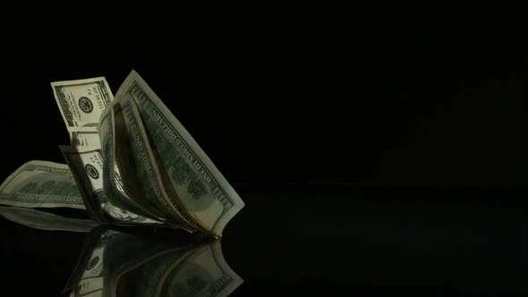 American $100 Bills Falling onto a Reflective Surface alt