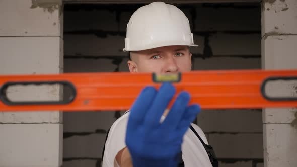 Portrait of a Male Construction Worker with a Construction Level in His Hands alt