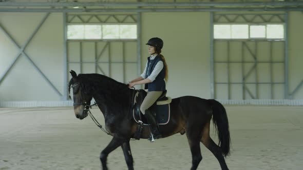 Female Jockey Riding Horse in Arena alt