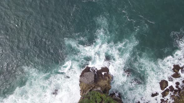 Top down aerial view of giant ocean waves crashing and foaming in coral beach alt