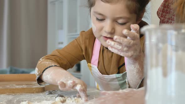 Mom and Daughter Prepare Holiday Cookies Together in the Kitchen. A Little Girl Helps Her Mother alt