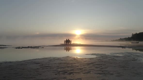 Couple in Love Sitting on a Bench in the Middle of the Lake and Meet the Sunrise alt