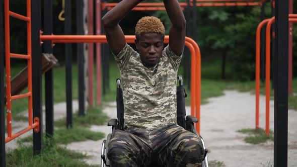 Confident Fit African American Man in Wheelchair Warming Up Outdoors with Sports Equipment at alt