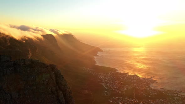 Dramatic Sunset Over the Ocean Featuring a Mountain Covered in Clouds