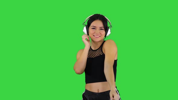 Charming Girl in Shorts and Earphones Dancing on a Green Screen, Chroma Key alt