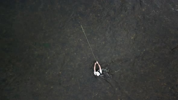 Bird's Eye Drone Shot above a man Fly Fishing in the Provo River in the Mountains of Utah. The man i alt