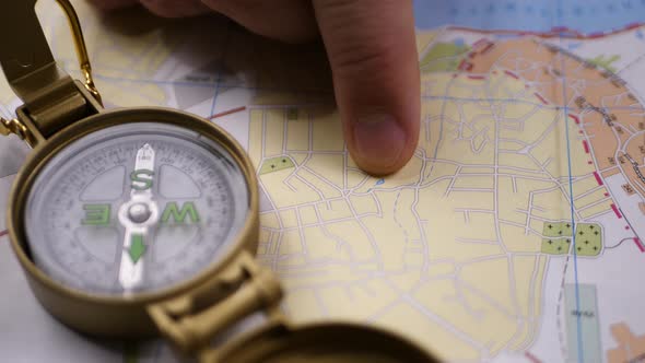 Male Hand Searching Direction on Map with Compass Background