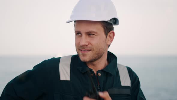 Marine Deck Officer Wearing Helmet and Safety Uniform Coverall Talking By Walkie Talkie alt