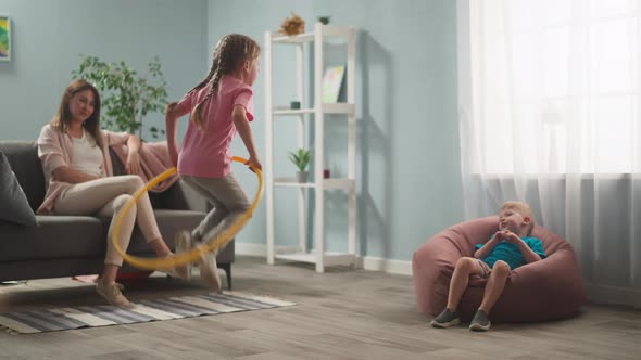 Young Woman Mother with Children Playing in Room Throwing Toys alt