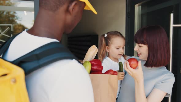 An AfricanAmerican Courier Brings a Package of Food Fruits and Vegetables in alt