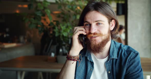 Hippie Man Talking on Smartphone in Cafe