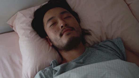 Sleeping Asian man sweet dreaming in the bedroom at home.