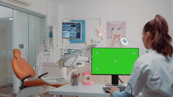 Woman Working As Dentist with Green Screen on Monitor alt