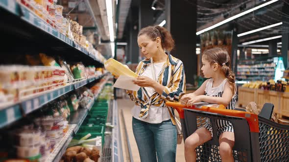 Woman Takes Packed Products From the Shelf Packed Mushrooms and Puts Them in a Trolley alt
