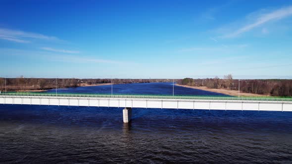 Concrete bridge across river, green metal railings on bridge