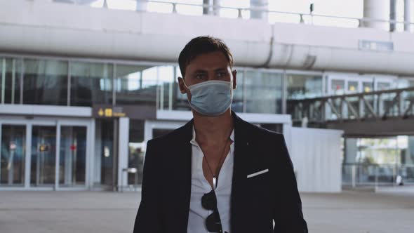 Young Male Traveler with Surgical Mask Walking Towards Camera in Airport alt