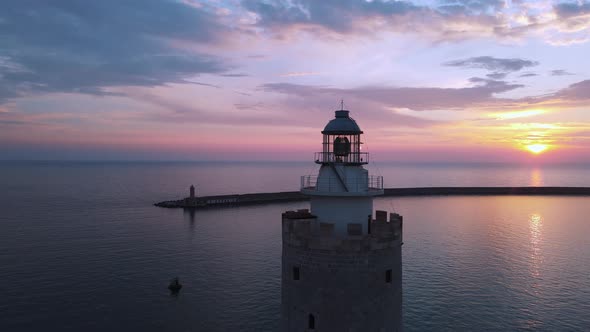 Aerial view of beautiful sunrise behind the dome and light of the lighthouse.
