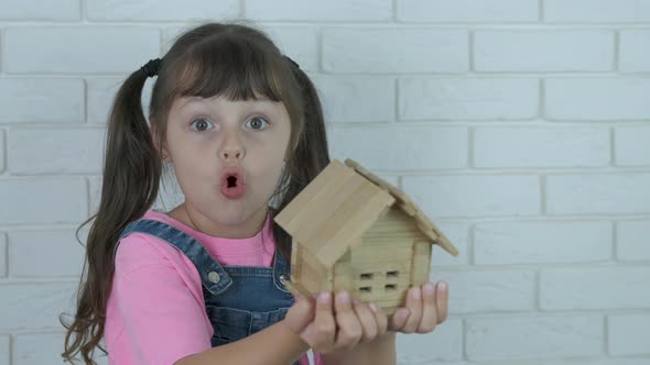 Child hold a wooden house.  alt