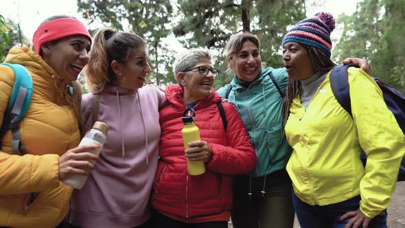 Group of women with different ages and ethnicities having fun walking in foggy forest alt