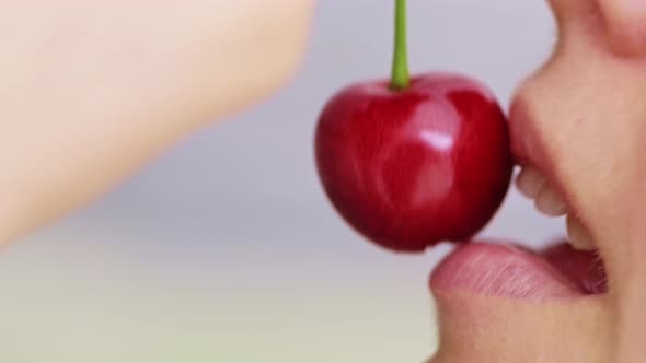 Macro of a Caucasian Young Girl is Biting Red and Ripe Wild Cherry