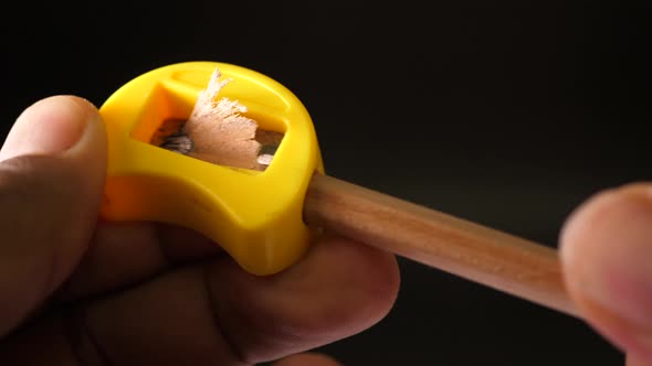 Sharpening a Pencil with a Sharpener on black background alt