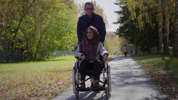 Woman on wheelchair with boyfriend at autumn park alt