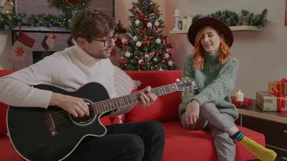 Happy young couple in winter sweaters enjoy Christmas and winter holidays singing Christmas songs. alt