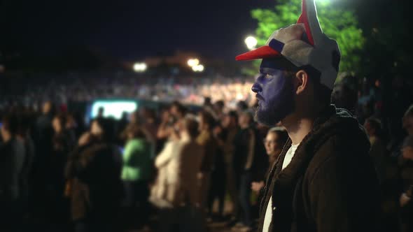 Football Fan Man Stand in Stadium Is Closely Watching Sport Game. Paint Face alt