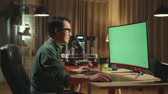 Asian Man Work On 3D Printer And Personal Computer With Mock Up Green Screen Display In Home Office alt