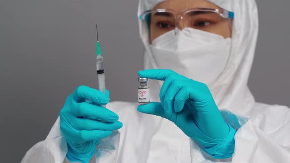 doctor in protective PPE suit holding Coronavirus(Covid-19) vaccine bottle and syringe