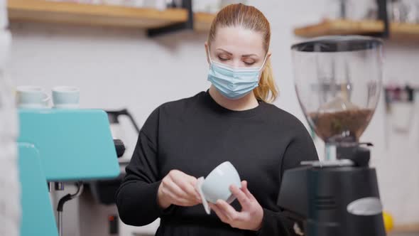 Concentrated Caucasian Woman in Covid19 Face Mask Cleaning Coffee Cup Before Making Hot Drink alt
