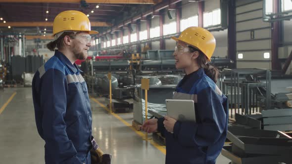 Male And Female Factory Workers Smiling And Shaking Hands alt