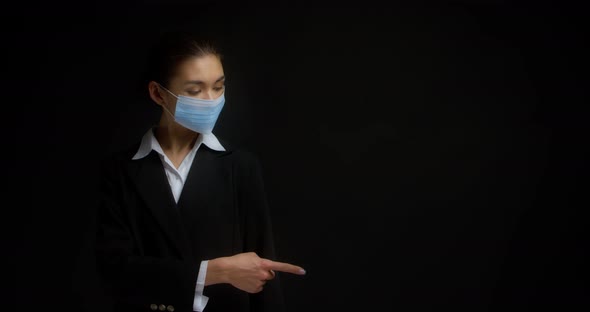 Brunette in a Medical Mask Points Her Index Finger to the Right