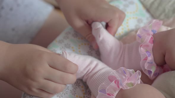 Boy playing with baby sister and rocking her in the chair alt