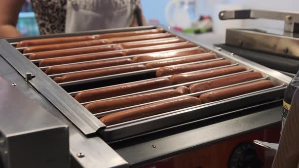 Hotdog Sausages Being Cooked on Grill on at Street Food Festival at Night. alt
