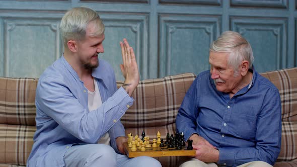 Happy Different Male Generations Family of Senior Father and Adult Son or Grandson Playing Chess alt