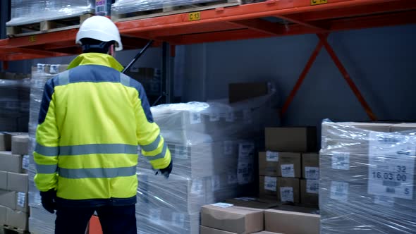 Follow footage of employees male warehouse worker engineer in hard hat working alt
