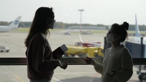 Two Women Tourists in Medical Mask Meet in Airport Terminal at Safe Distance Before Flight and Greet alt