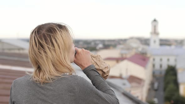 Woman drinking alcohol on a roof alt