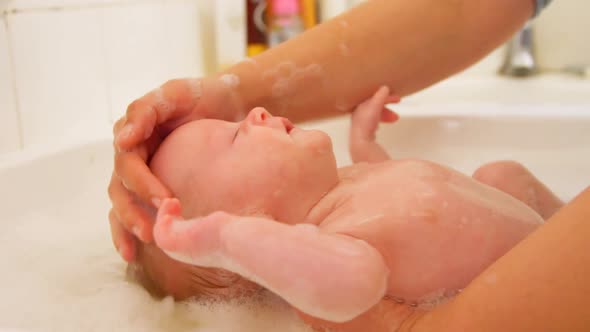 Mother giving her baby boy a bath in bathroom 4k alt