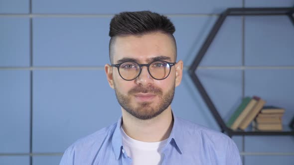 Close up of Caucasian handsome man in white shirt in glasses looking straight in the camera alt