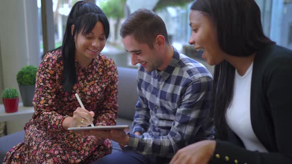 Cheerful multiethnic friends browsing on tablet alt