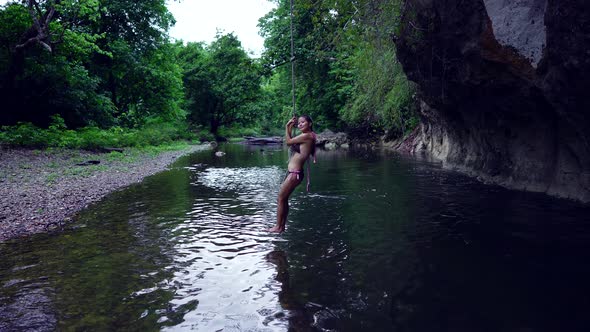 Cute Smiling Asian Girl in Bikini Chilling on a Rope in the River Thailand