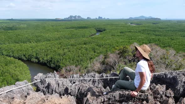 A woman sitting on the mountain peak while traveling the mangrove forest viewpoint