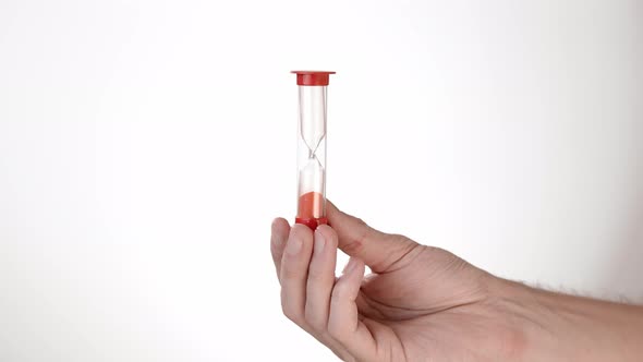 Time Begins. A Man's Hand on a White Background of Isolate Holds an Hourglass and Turns It Over alt