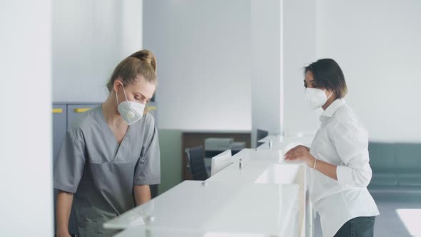 Hospital Reception a Nurse Registers an Young Woman Patient for a Doctor's Appointment in a Modern alt