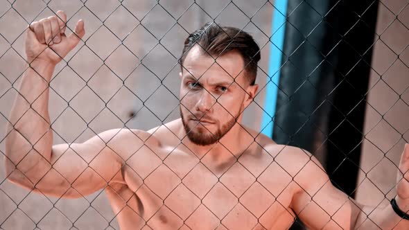 An Attractive Man Boxer Standing Behind the Net in the Gym alt