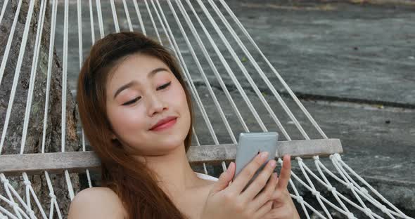 Summer Vacation of happy Asian woman wearing white bikini using mobile phone alt