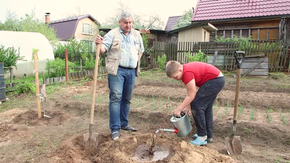 Father and Son Planted a Tree the Boy Poured Water From a Watering Can alt