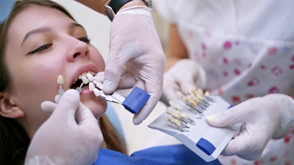 Woman in stomatological cabinet. Professional stomatologist holding dental crown for female patient alt